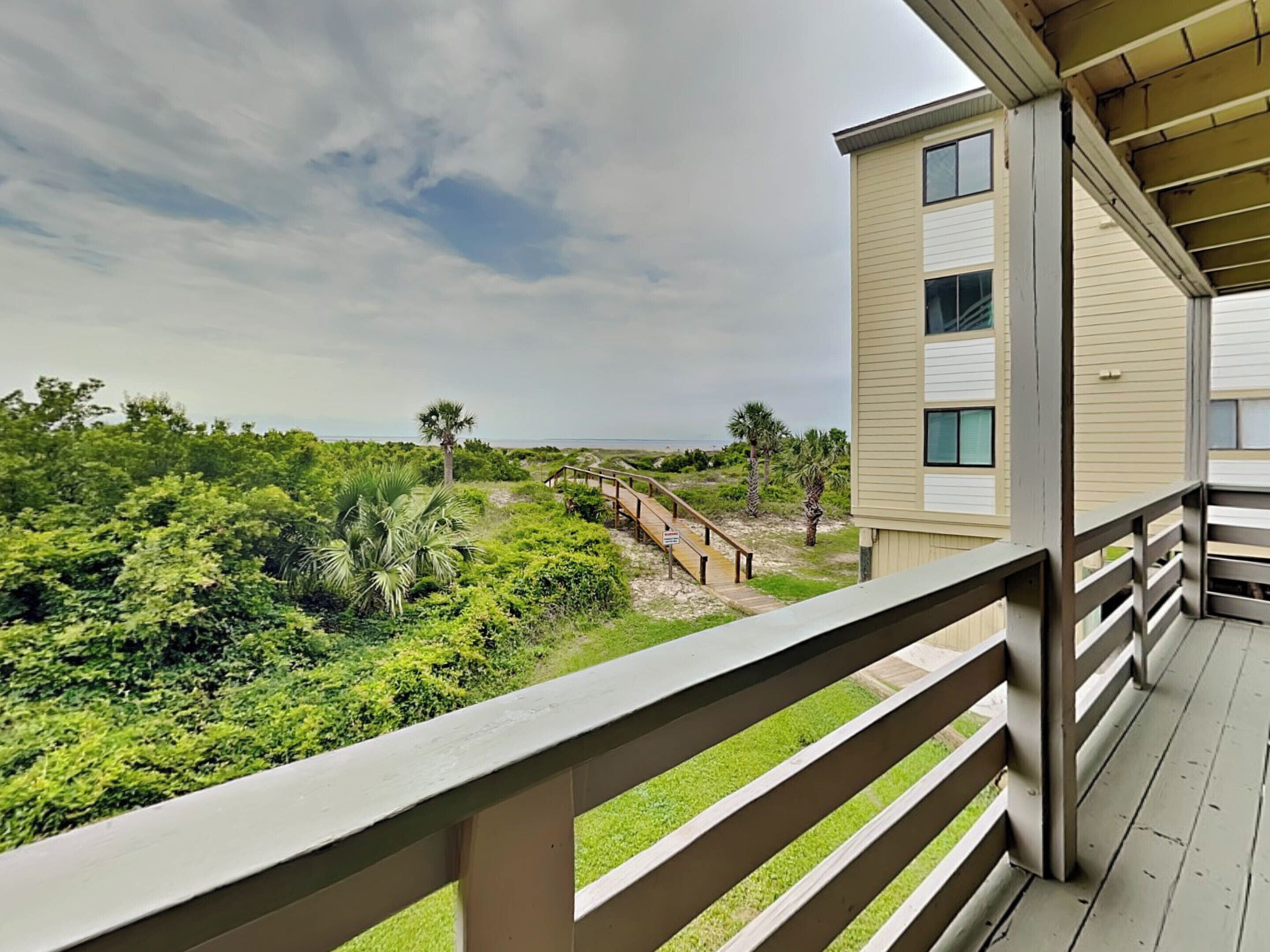 Ein Balkon mit Blick auf einen Strand und üppiges Grün.