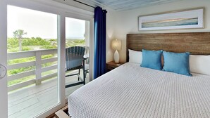 Un dormitorio con una cama grande, una mesita de noche, una silla y vistas al exterior.