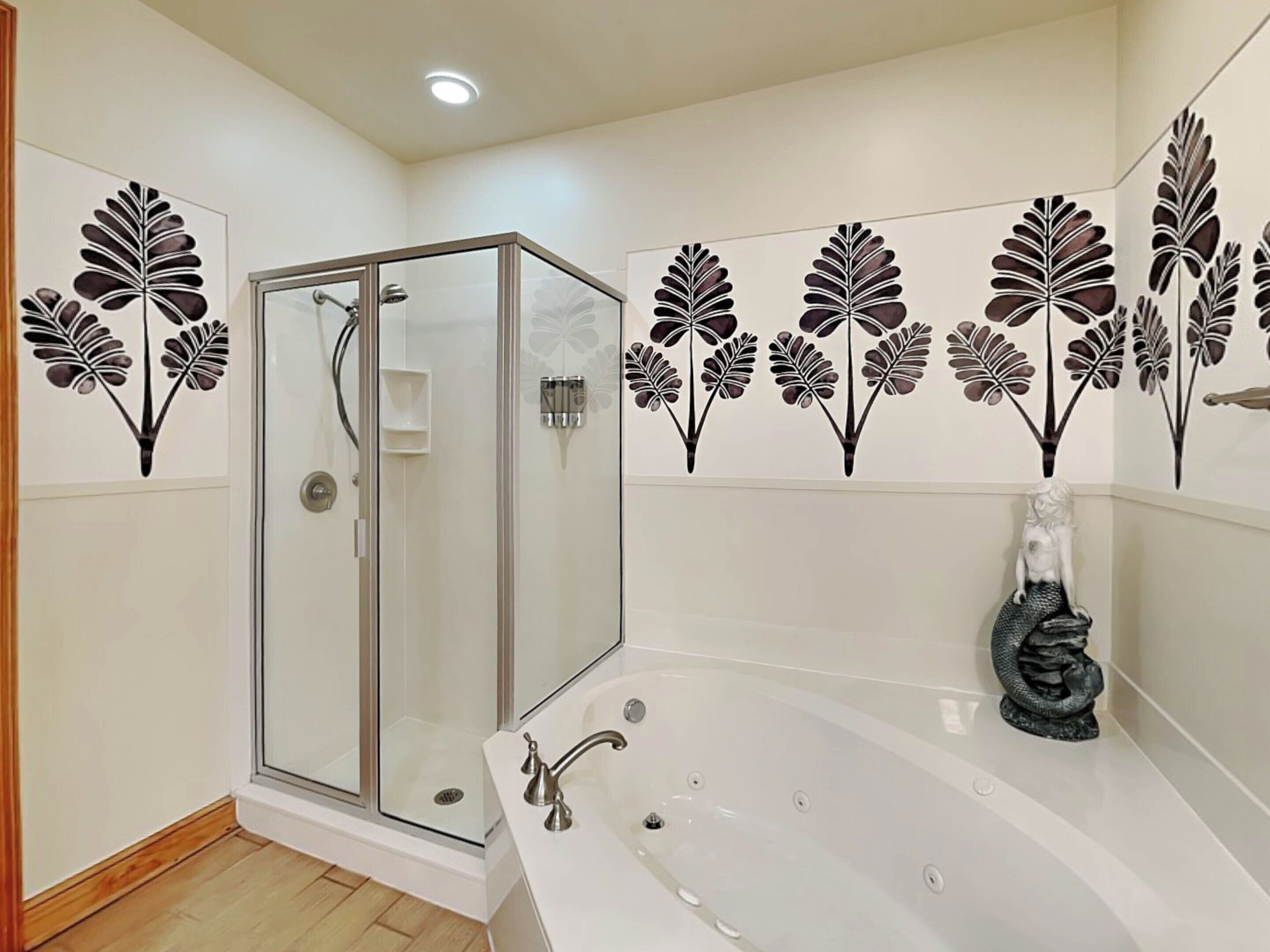 Une salle de bain moderne dotée d’une douche à parois de verre, d’une baignoire sur pieds et de carreaux décoratifs recouvrant les murs.
