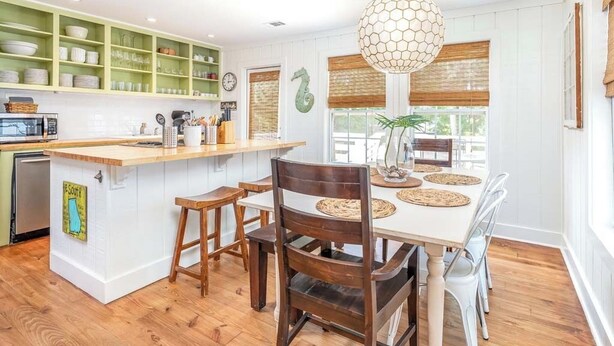 A kitchen with a wooden island, white cabinets, and a hanging light fixture. - Just Beachy Tybee Vacation Rentals (Tybee Island)