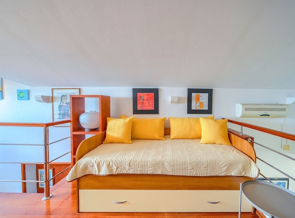 A hotel room with a bed, a bedside table, a chair, and artwork on the walls.