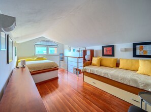 A bedroom with a bed, a desk, a chair, and a window.