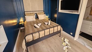 Een slaapkamer met een bed, nachtlampen, een televisie en een klein tafeltje.
