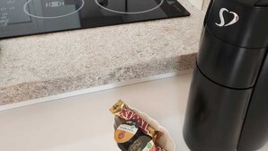 A kitchen with a black induction cooktop, a stainless steel sink, a red cup, and a trash bin. - In Perdizes, a very well-equipped studio apartment near Allianz Parque and PUC university. (City of Sao Paulo)