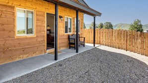 Eine Holzhütte mit überdachter Veranda, Kiesgrund und Holzzaun.