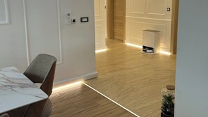 A modern interior with a dining area featuring a marble table and chairs, a wooden floor, and recessed lighting.