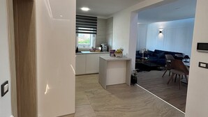 A modern kitchen with white cabinets, a central island, and a dining area with a sofa and chairs.