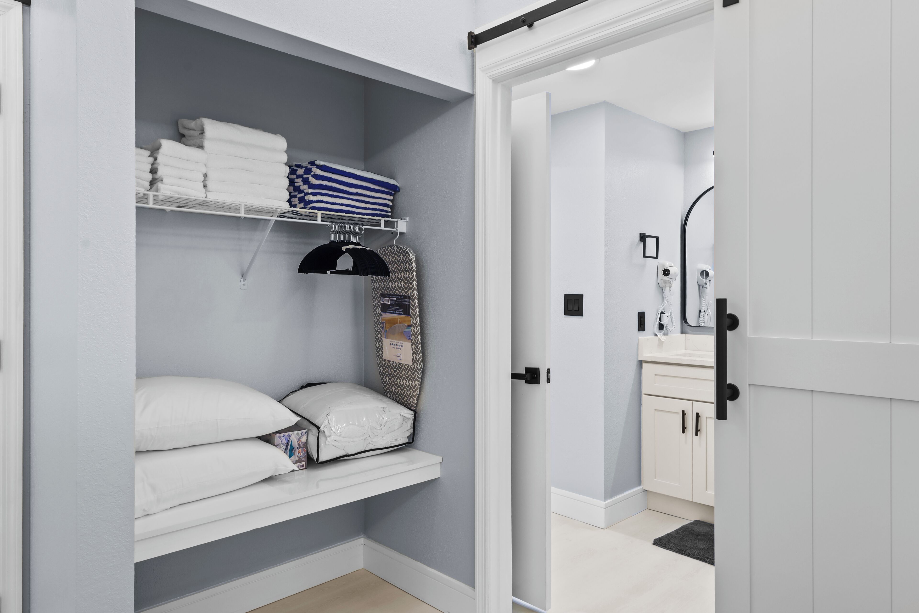 Un'area dispensa ordinata con scaffali su cui sono piegati asciugamani e una coperta.