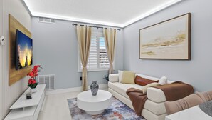 A modern living room with a white sofa, a coffee table, and a painting on the wall.