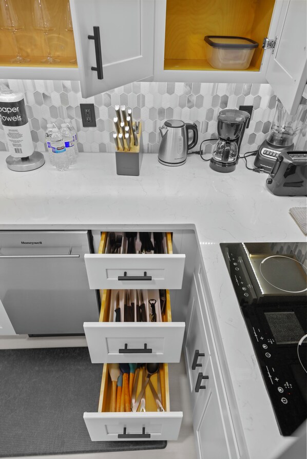 A kitchen with white cabinets, a Honeywell dishwasher, a coffee maker, and a blender on the counter.