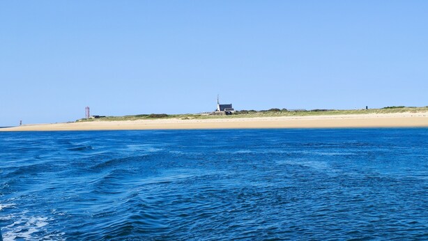 A coastal scene with a lighthouse on a sandy beach, clear blue sky, and calm sea. - New house, spacious, bright, quiet neighborhood in agglo, fenced. Garage (Plouharnel)
