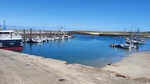 A marina with boats docked, a large ship named 'Melvan Lorianet', and a lighthouse in the background. - New house, spacious, bright, quiet neighborhood in agglo, fenced. Garage (Plouharnel)