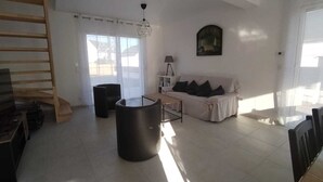 A spacious living room with a sofa, a coffee table, and a large black cylindrical object. - New house, spacious, bright, quiet neighborhood in agglo, fenced. Garage (Plouharnel)