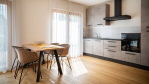 A modern kitchen with wooden cabinets, a built-in oven, and a dining area with a table and chairs.