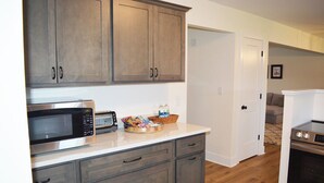 A kitchen with wooden cabinets, a microwave, a toaster, and a basket of magazines. - Home in Frankfort countryside-close to distilleries, Keeneland &Churchill Downs! (Frankfort)