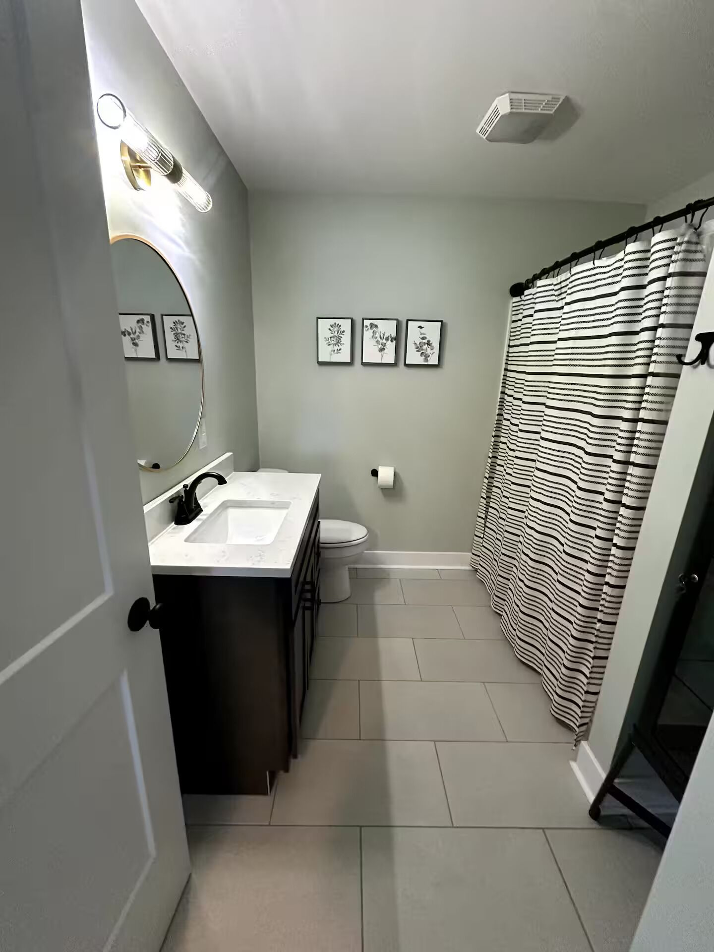 A modern bathroom with a sink, toilet, and shower curtain.