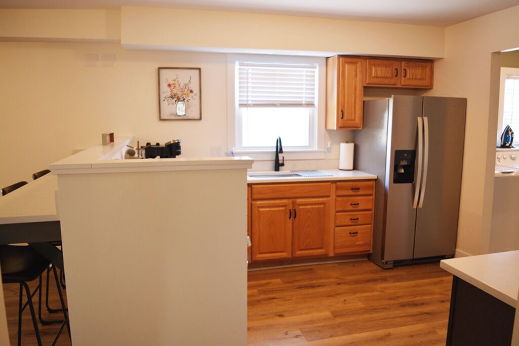 A kitchen with wooden cabinets, a stainless steel refrigerator, and a white countertop.