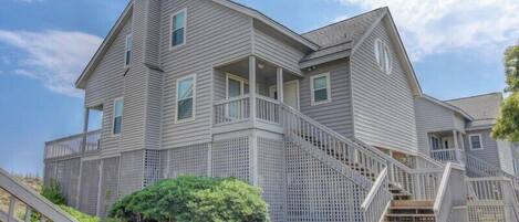 A two-story house with a covered porch and a staircase leading to the upper level.