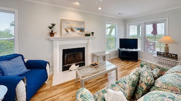 Una sala de estar con chimenea, televisor, mesa de centro y sofá.