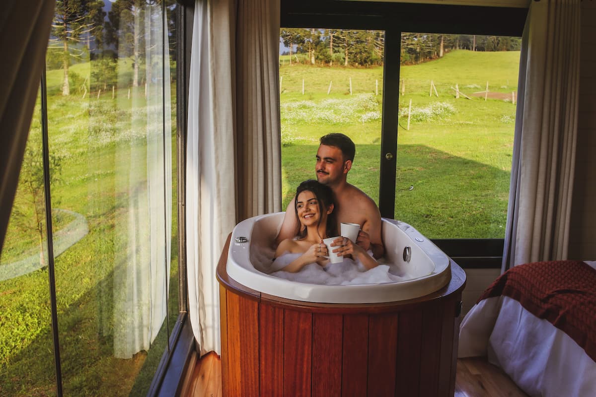 A couple in a hot tub with a view of a grassy area and trees.