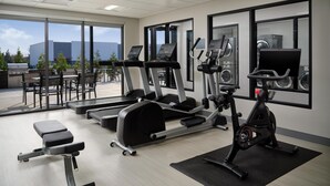 A gym with treadmills, an elliptical, and a stationary bike. There are outdoor seating areas and a view of the city. - Hyatt Studios Huntsville (Huntsville)