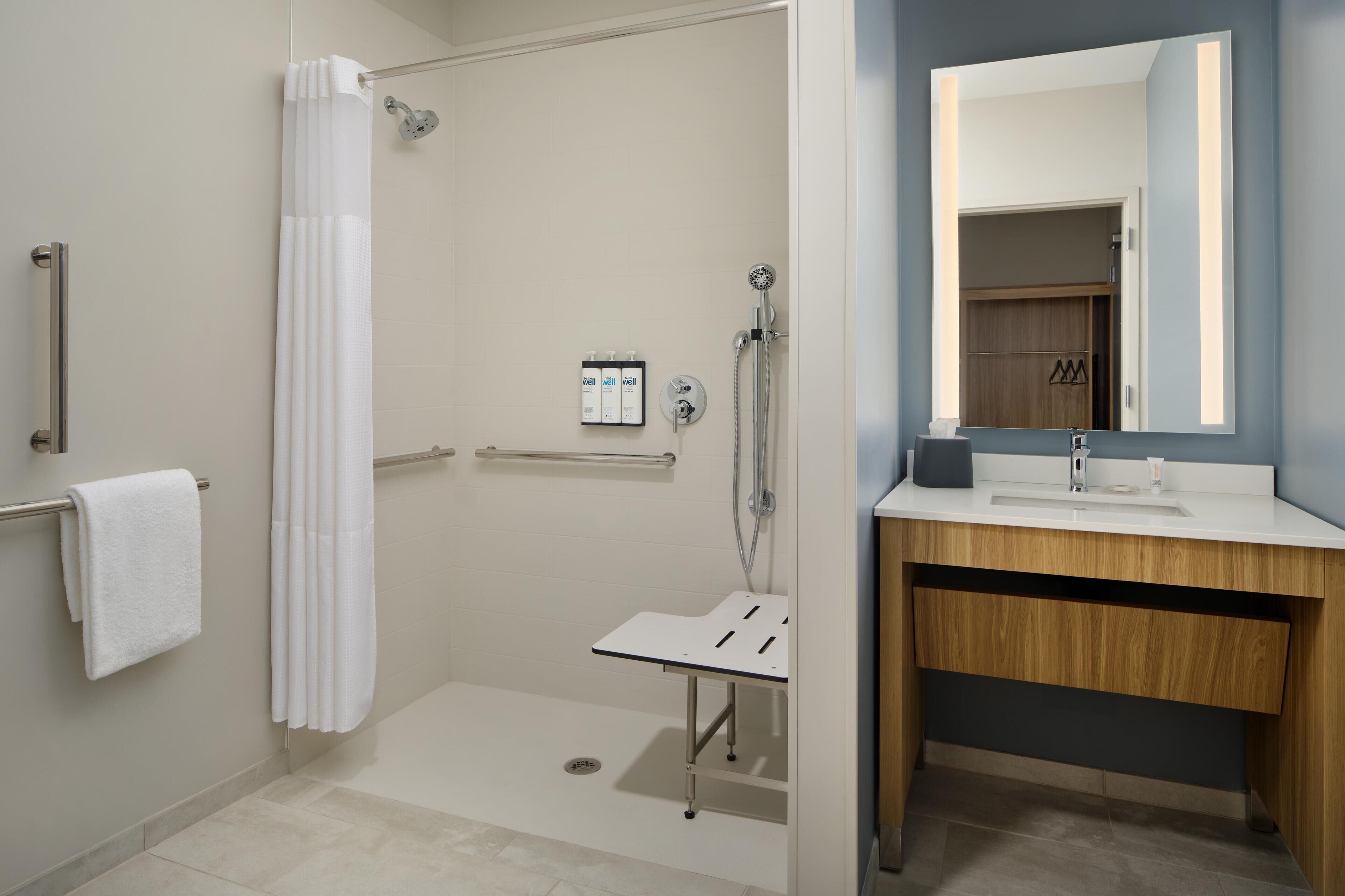 A modern bathroom with a shower, a sink, and a mirror.