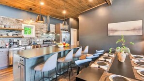 Une cuisine moderne dotée d’un îlot central, de tabourets de bar et d’une table à manger pour six personnes.