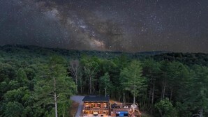 Une cabane entourée d’une forêt dense, offrant une vue dégagée sur le ciel nocturne.
