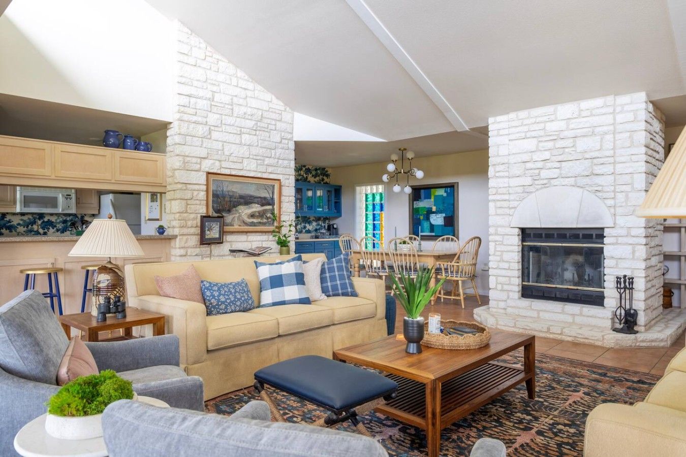 A living room with a fireplace, a sofa, a coffee table, and a dining area with chairs.