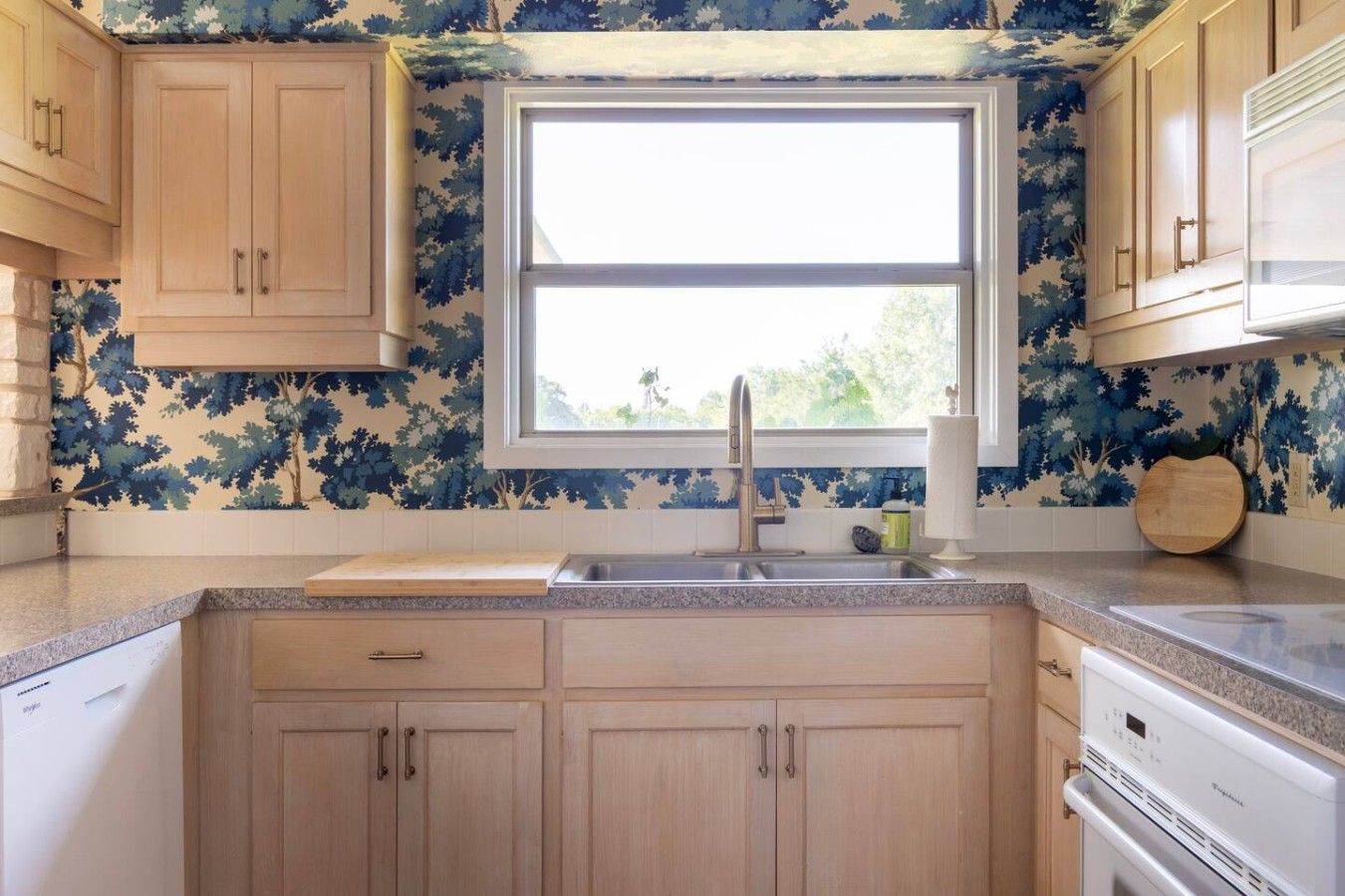 A kitchen with wooden cabinets, a window, a sink, and a countertop.