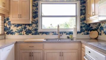 A kitchen with wooden cabinets, a window, a sink, and a countertop.