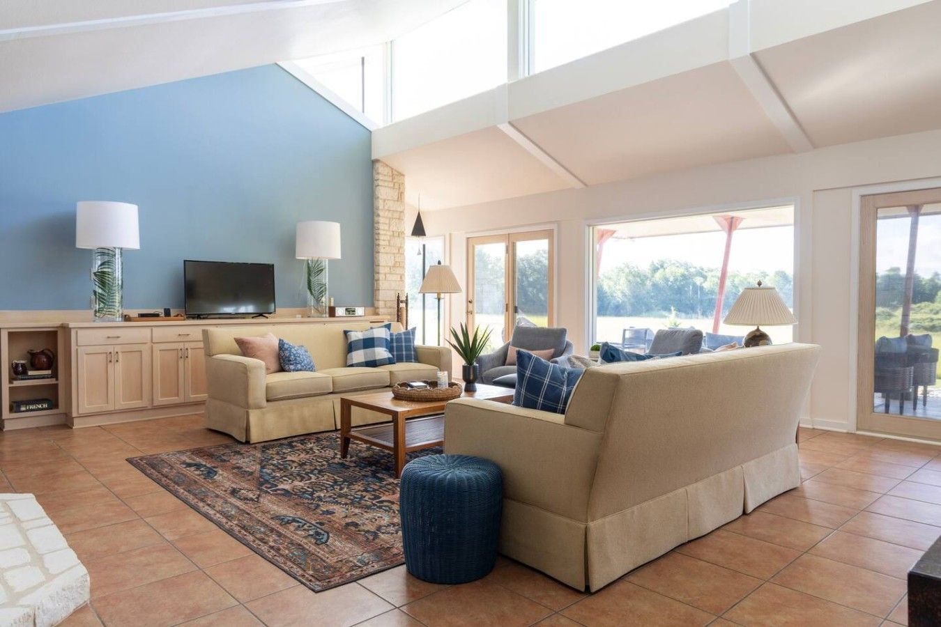 A spacious living room with a high ceiling, a large window, and a view of the outdoors.