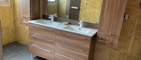 A bathroom with a double sink vanity, wooden cabinets, and a large mirror.