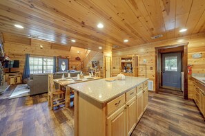 Interior de una cabaña de madera con cocina, comedor y sala de estar con chimenea.