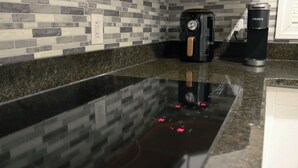 Una cocina con encimera negra, cafetera y máquina de café Keurig.