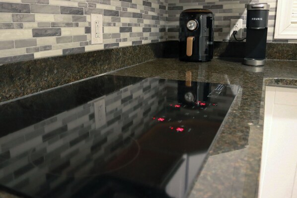 A kitchen with a black countertop, a coffee maker, and a Keurig coffee machine.