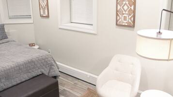 A bedroom with a bed, a chair, a lamp, and a small table.