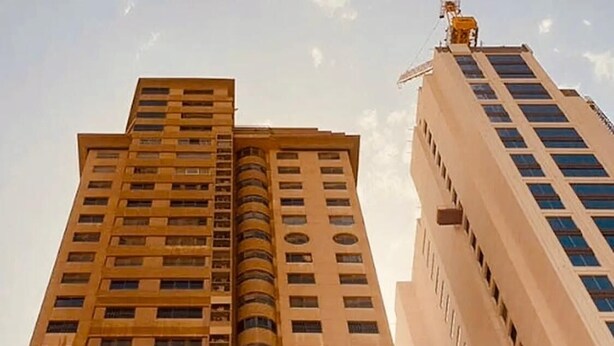 Un edificio de gran altura con varios pisos, ventanas amplias y una columna central destacada.