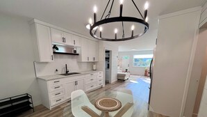 A modern kitchen with white cabinets, a glass dining table, and a chandelier. - Alpine Escape-Completely Renovated Home, 20 minutes from Jasper Park Gates (Hinton)