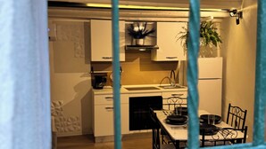 Uma cozinha moderna com armários brancos, bancada preta e área de jantar com mesa e cadeiras.