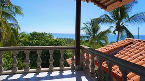 A balcony with a view of the ocean and palm trees.