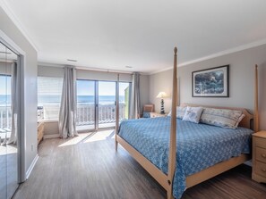 Ein Schlafzimmer mit Himmelbett, einem Balkon mit Meerblick und einem Bild an der Wand.