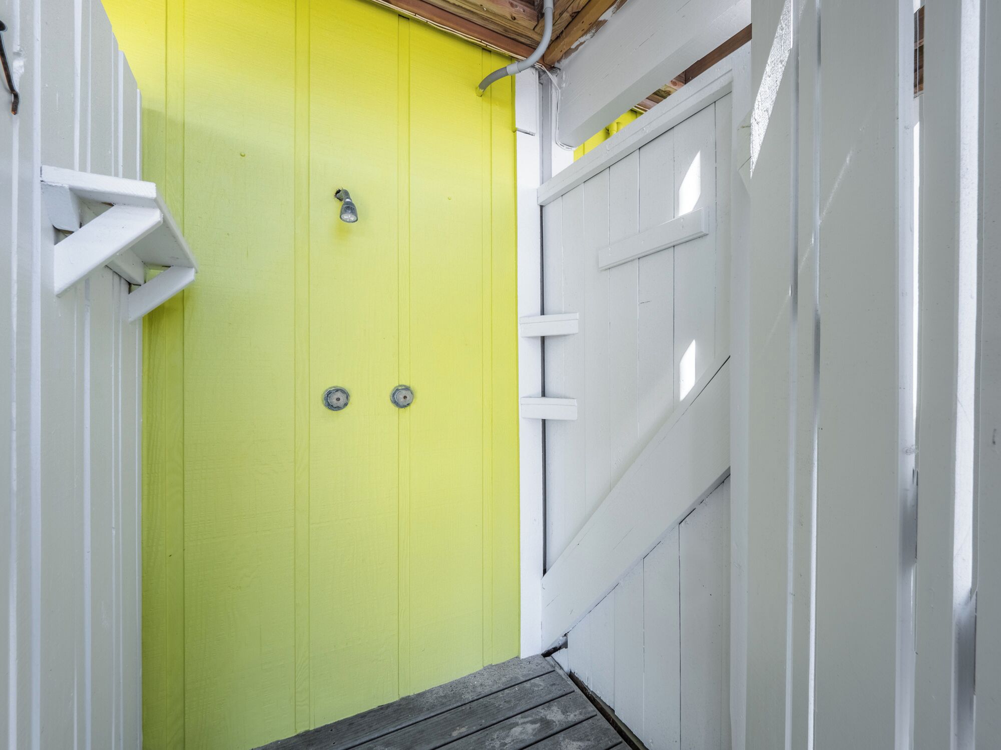 A narrow hallway with a bright yellow door and white walls.
