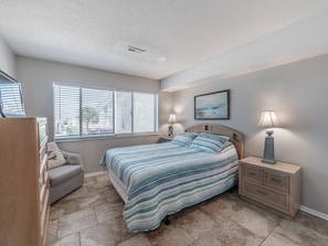 A bedroom with a bed, bedside tables, a dresser, and a window with blinds.