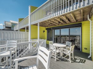 Eine Terrasse mit weißen Stühlen und einem Tisch, mit Blick auf eine schöne Aussicht.