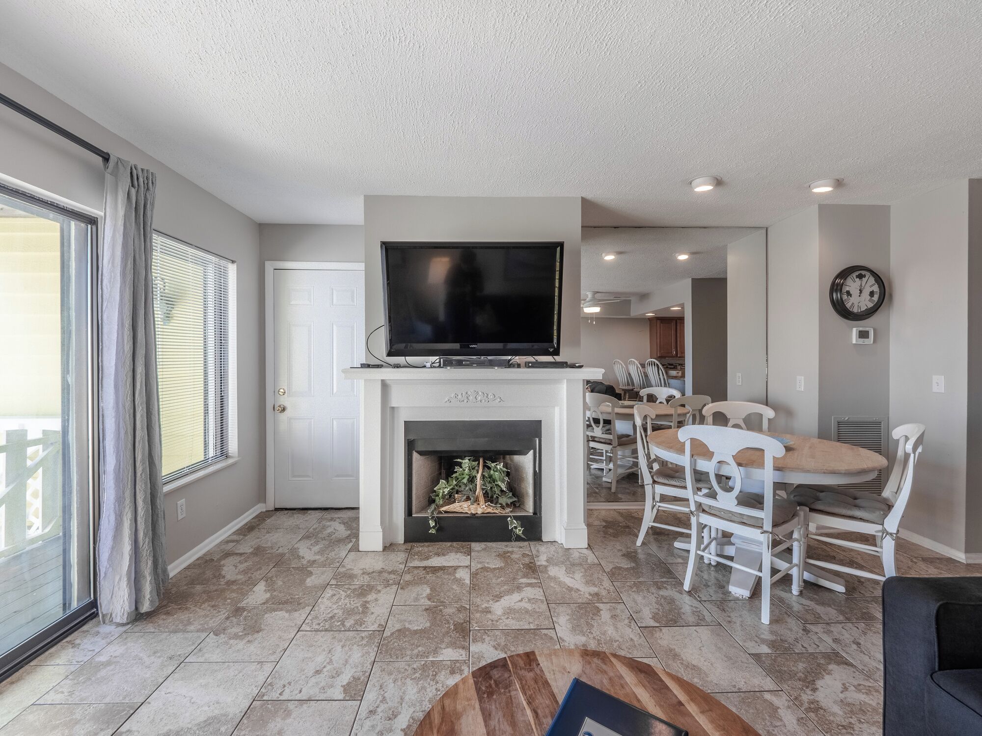 A living room with a fireplace, a television, and a dining area with chairs.