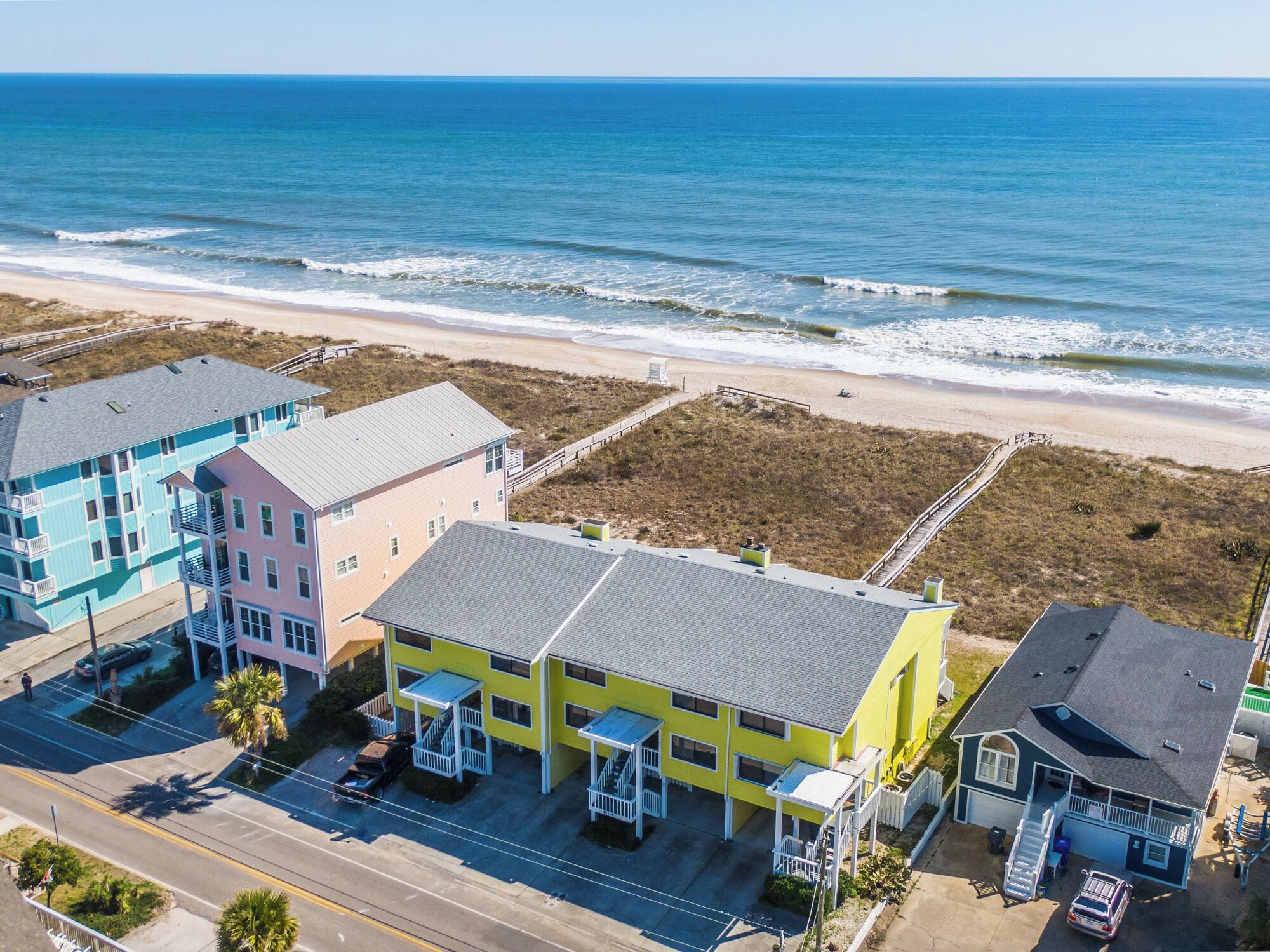 A coastal building complex with multiple structures, including a two-story building with a balcony and a single-story building with a covered porch.