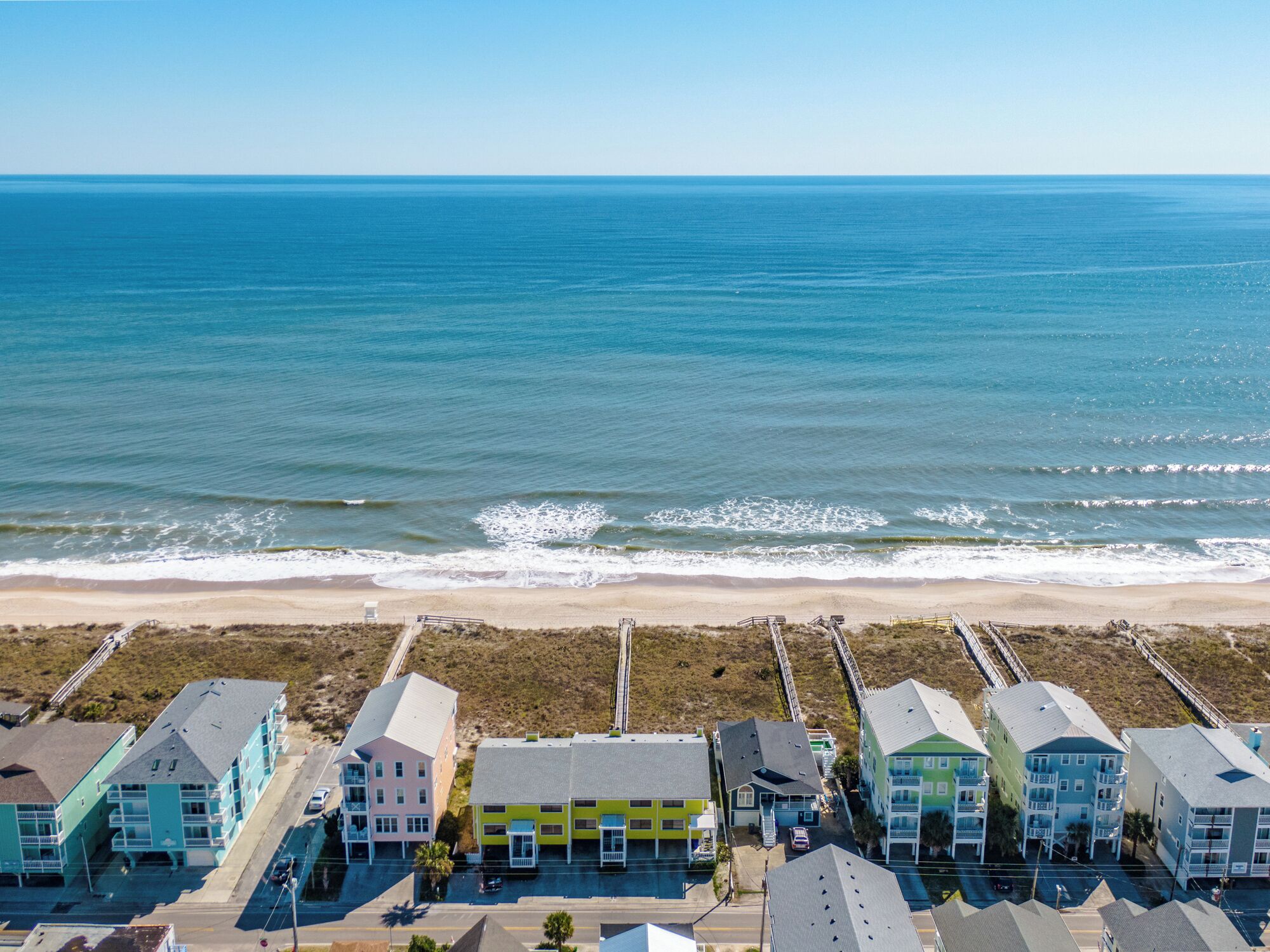 A coastal hotel with colorful buildings, a beach view, and a parking area.
