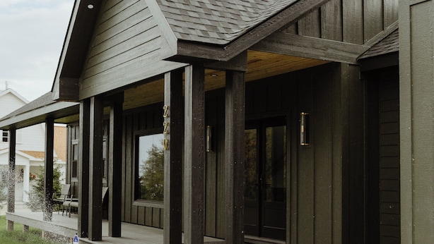 A modern building with a covered porch, large windows, and a dark exterior.