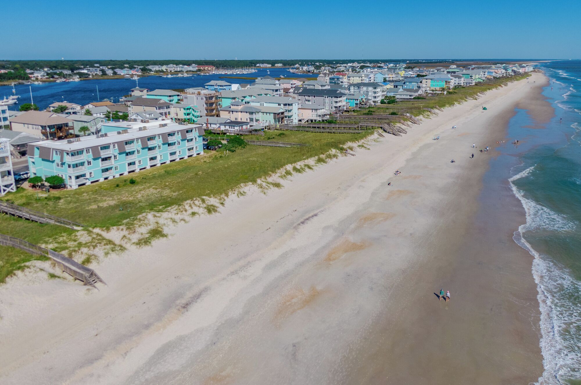 Un hôtel situé sur la côte, composé de plusieurs bâtiments à étages, avec une plage de sable et une vue sur l’océan.